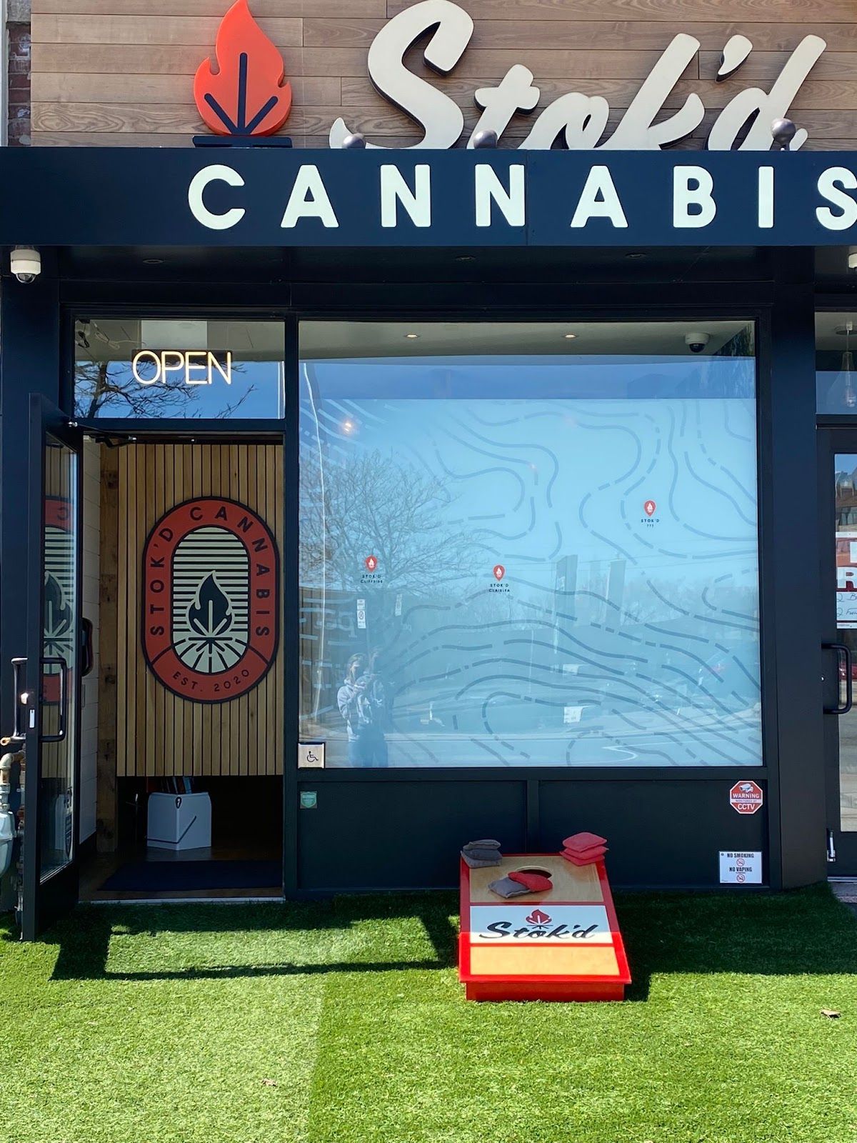 Storefront of Stolid Cannabis with blue window, green turf, and an open door sign