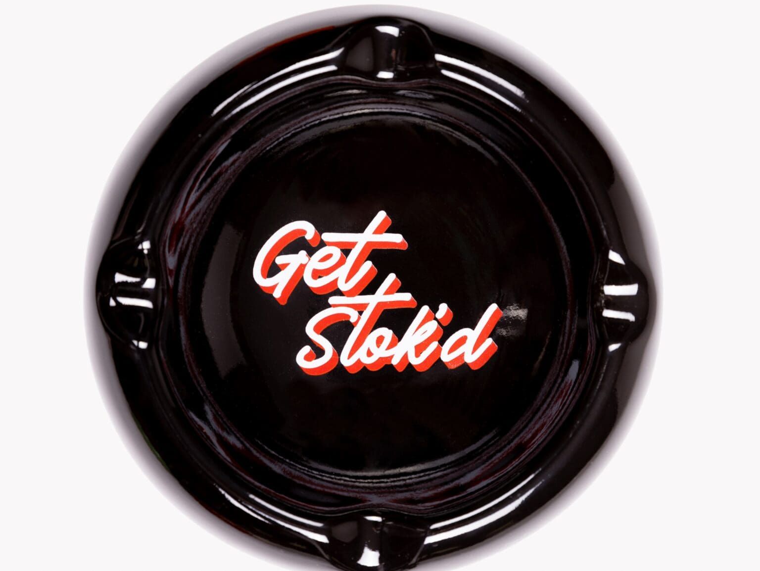 Black circular ashtray or plate with red-and-white “Get Stkkd” text in the center