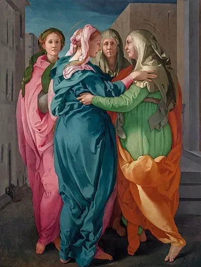 Quattro figure in abiti dai colori vivaci si radunano in una strada stretta, con due figure centrali che si abbracciano nella Visitazione.