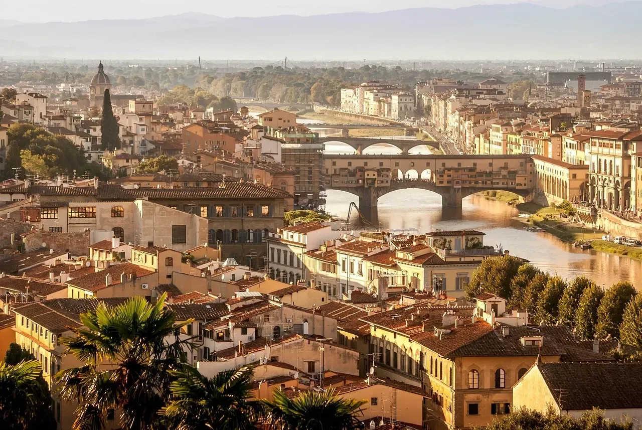 Veduta panoramica del Ponte Vecchio che attraversa il fiume Arno a Firenze, Italia, circondato da edifici storici.