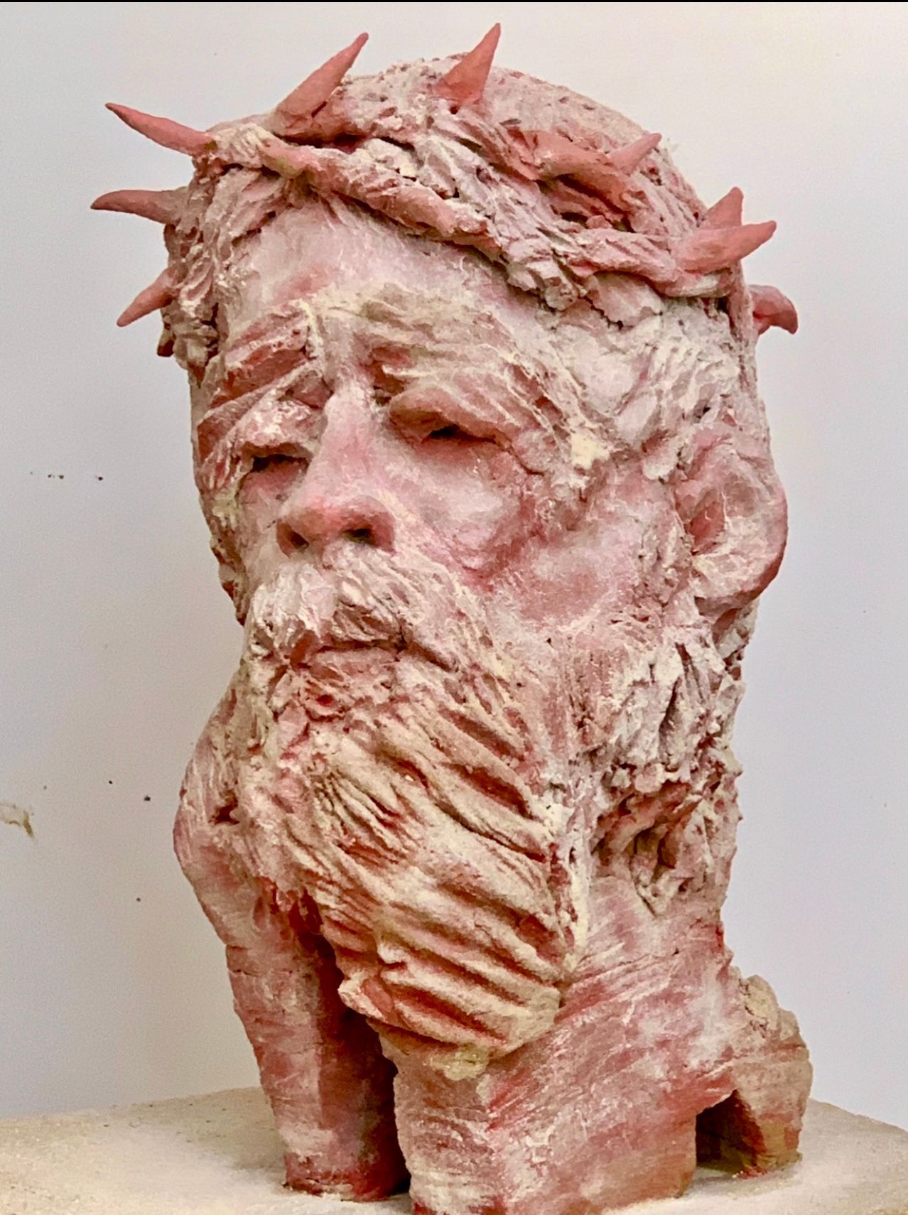 Rosafarbene Skulptur eines bärtigen Gesichts mit stacheligen, kronenartigen Auswüchsen und rauer Oberfläche