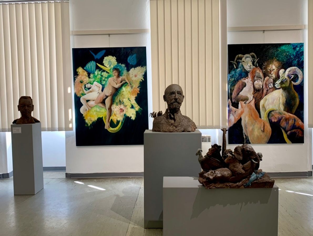 Skulpturengalerie mit Büsten auf Sockeln und farbenfrohen figurativen Gemälden an den Wänden.