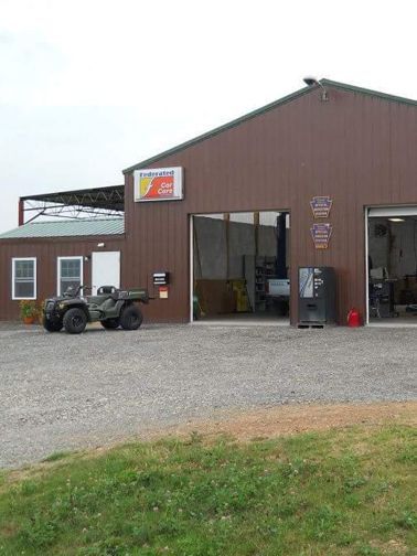 Brown building with open garage doors. An ATV sits in front.
