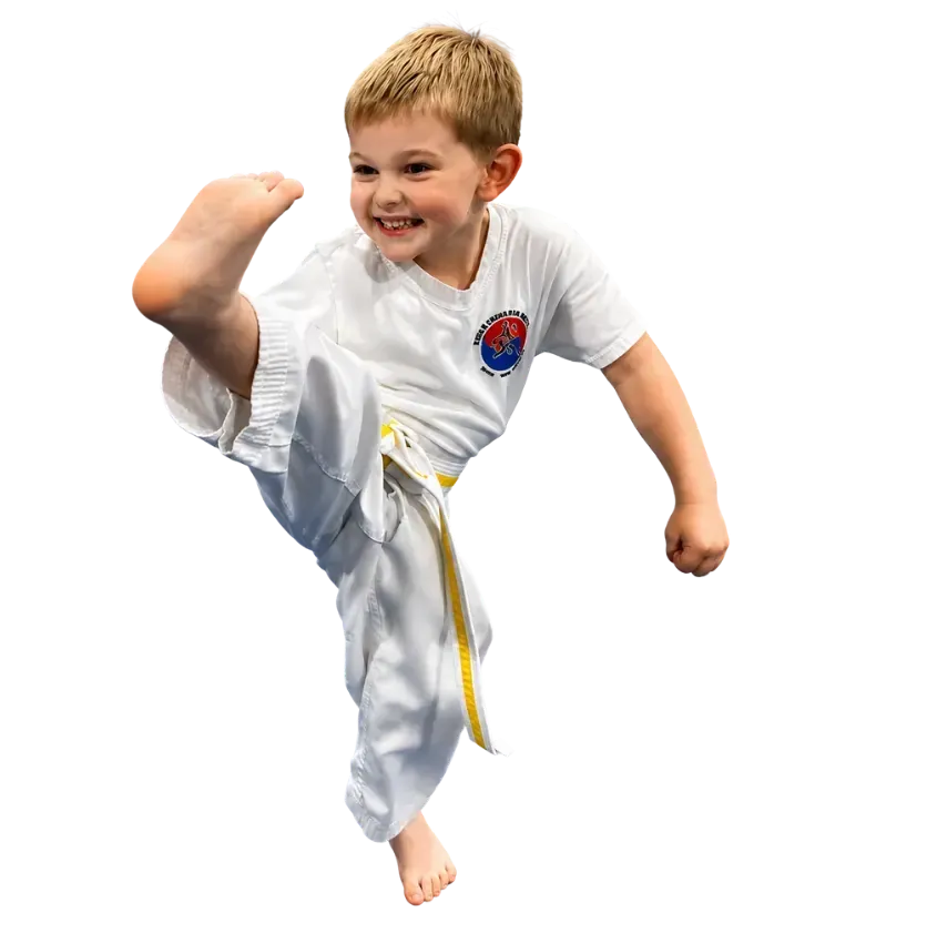 Young child in a white martial arts uniform doing a high kick on a white background