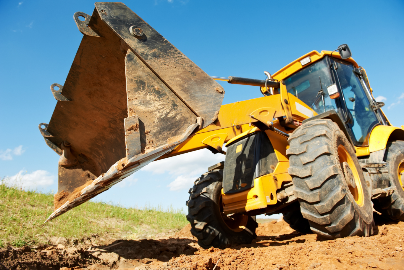 A yellow bulldozer is moving dirt in a field.
