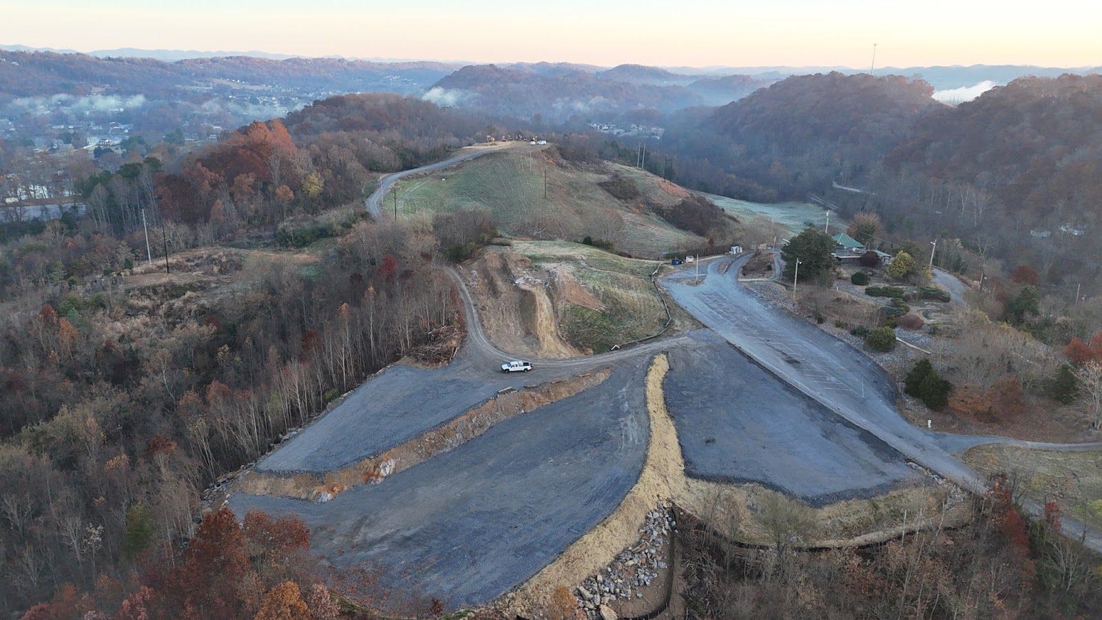 An aerial view of a road going through a forest on top of a hill.