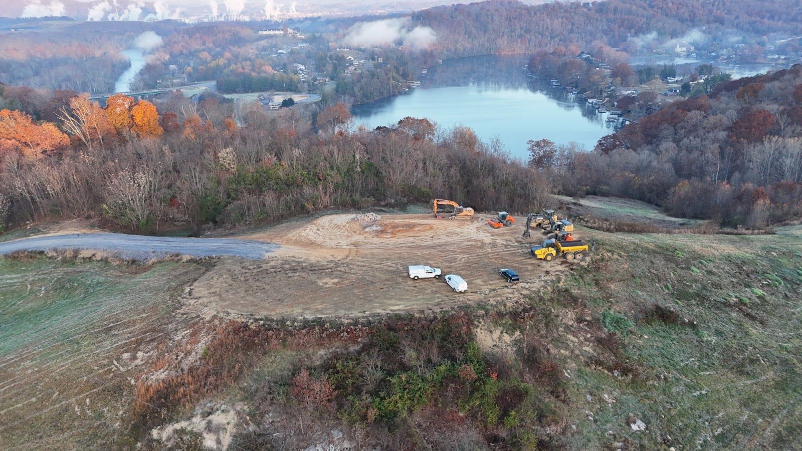 An aerial view of a construction site with a lake in the background.