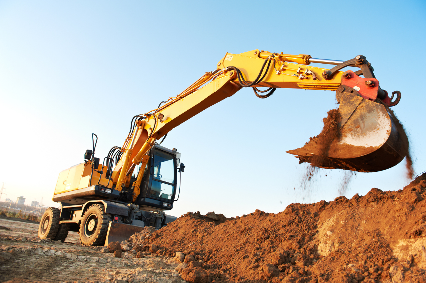 FREE Estimate A yellow excavator is digging a pile of dirt on a construction site.