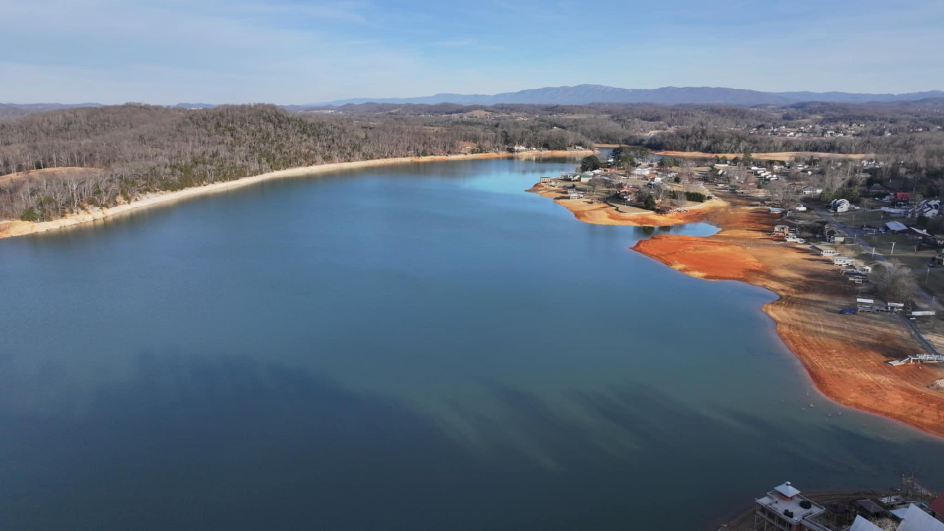 An aerial view of a large lake with mountains in the background.