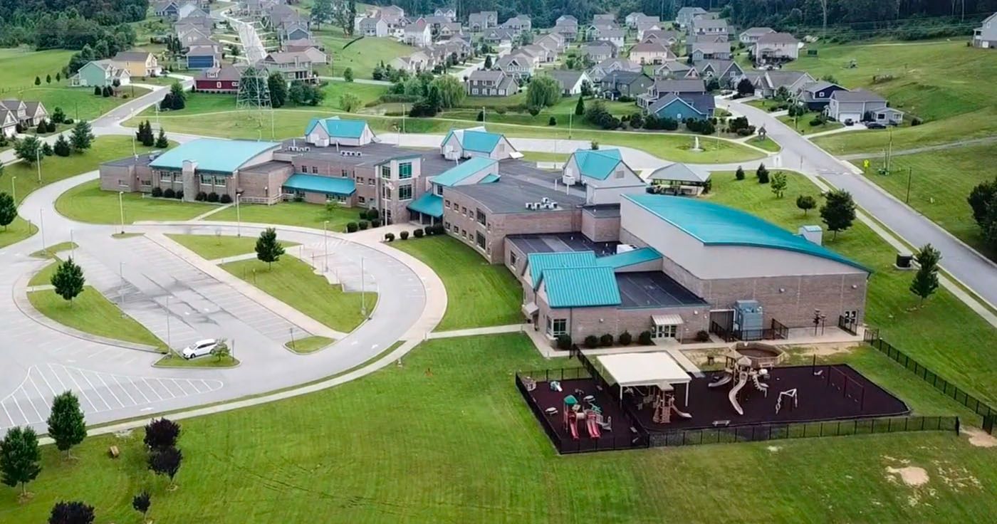 An aerial view of a school with a playground in front of it