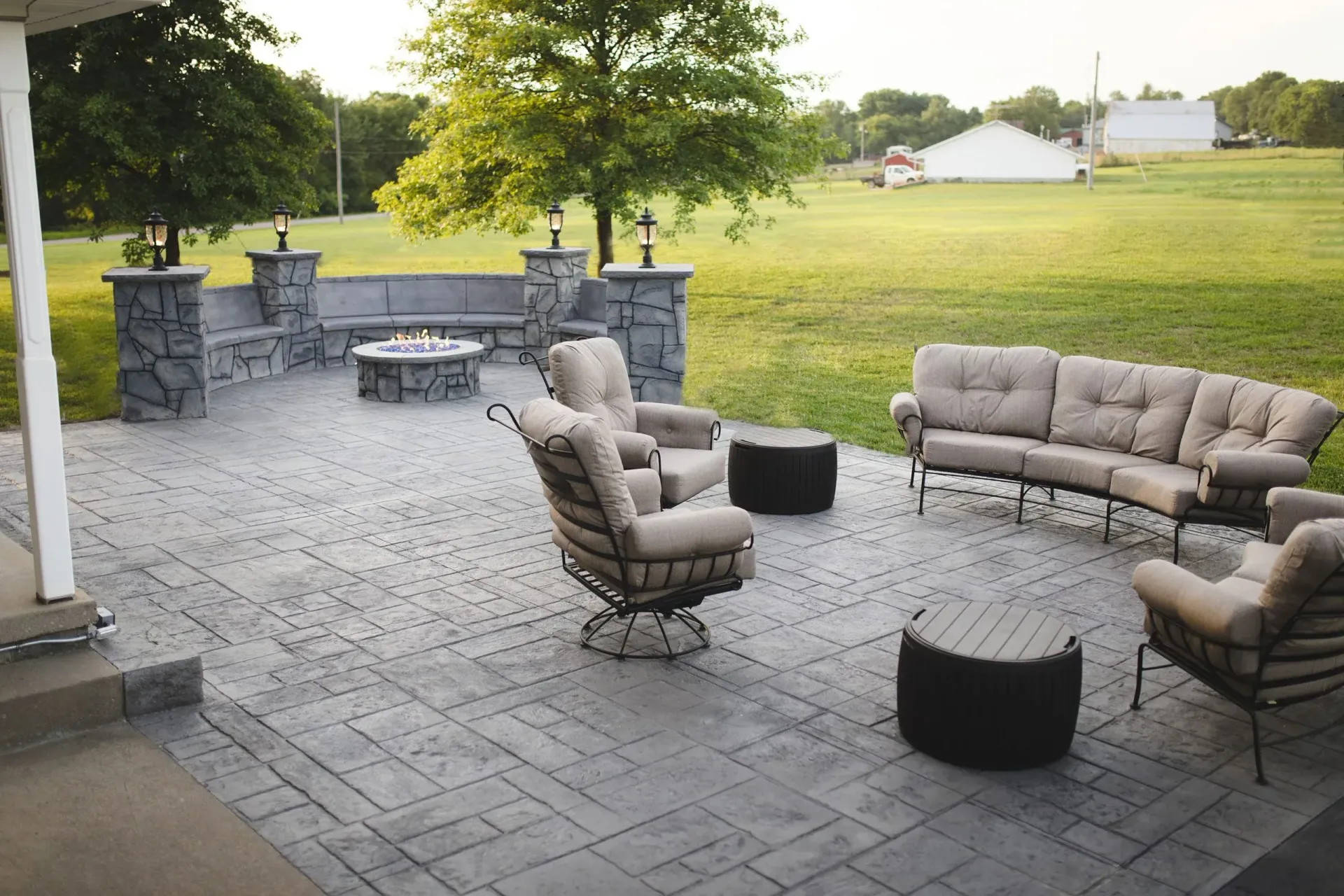 Patio with cushioned outdoor seating, stone fire pit, and a grassy yard beyond