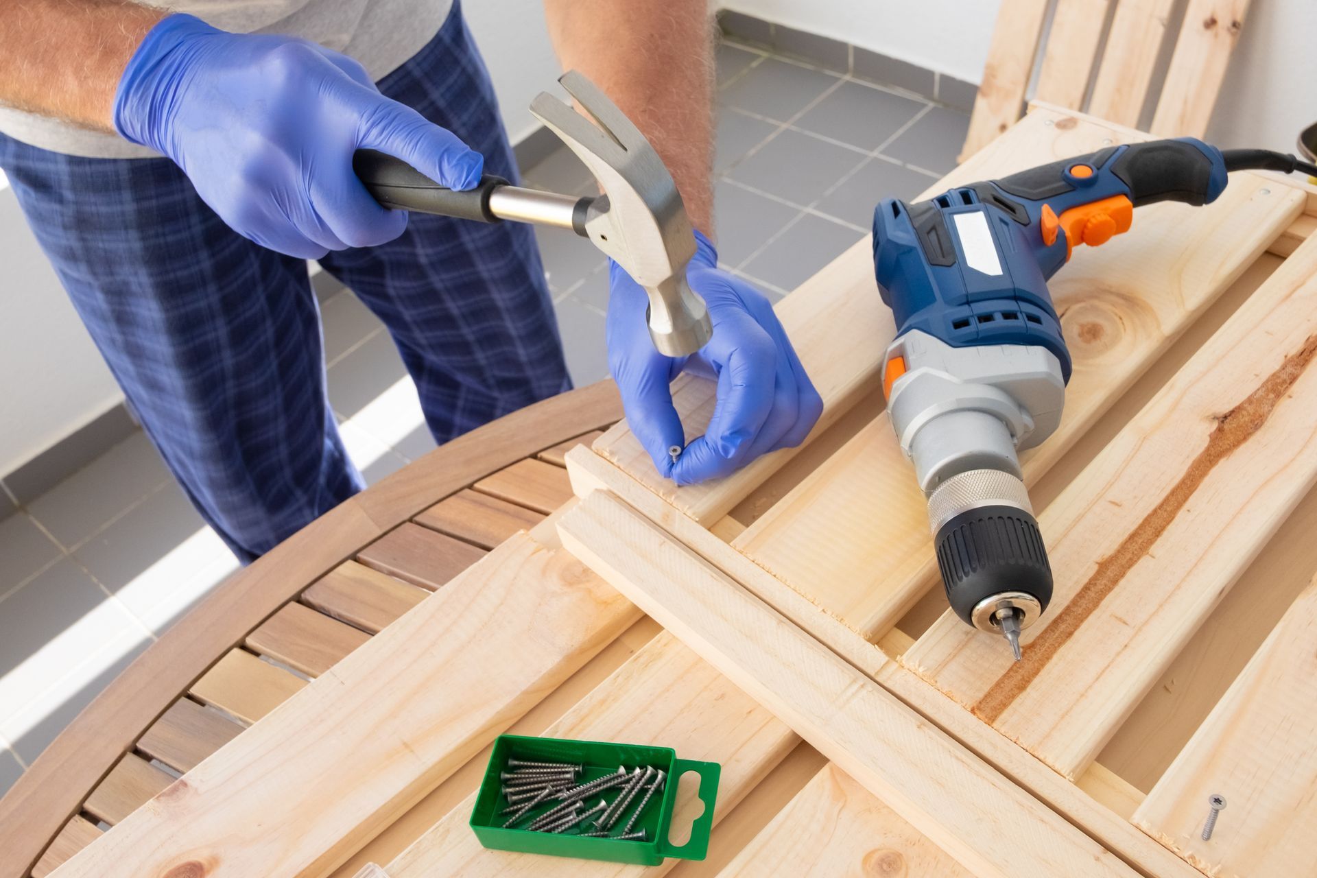 A man is hammering a nail into a piece of wood.