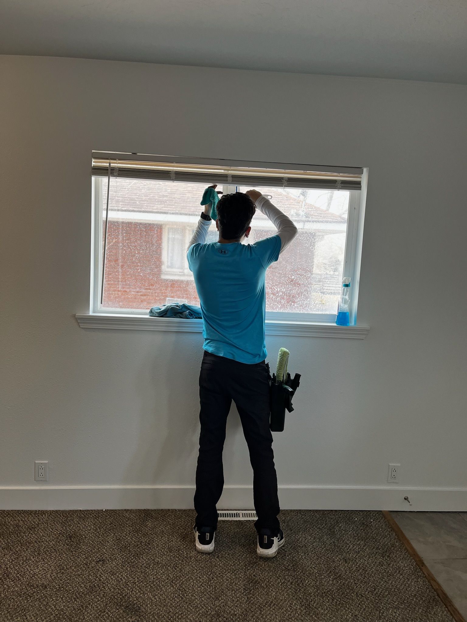 A man is cleaning a window in a living room.