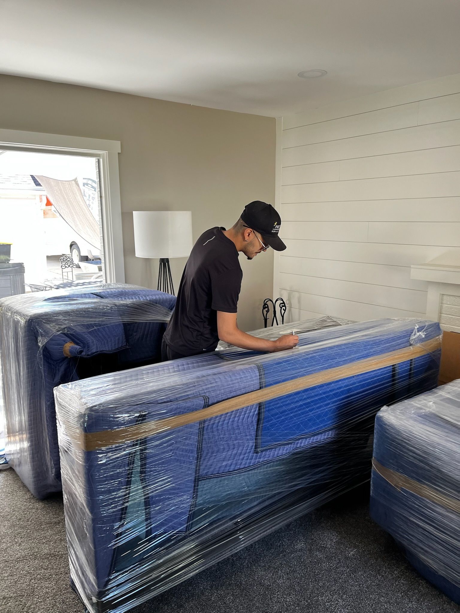A man is packing a couch in a living room.
