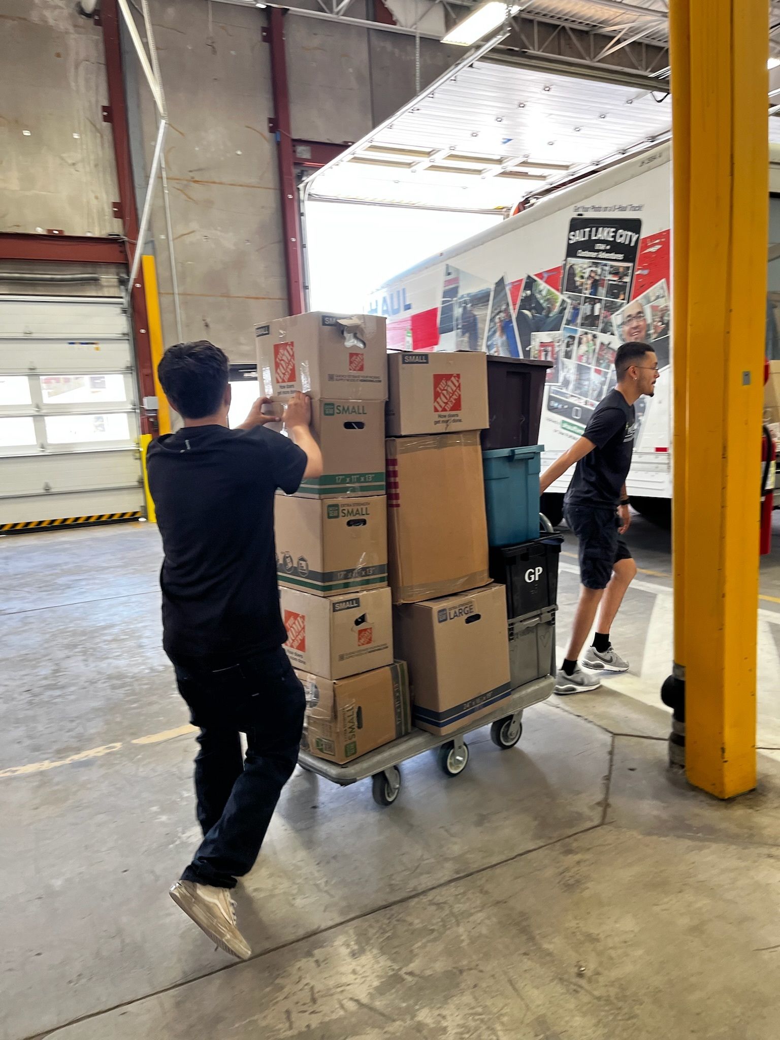 A man is pushing a cart full of boxes in a warehouse.