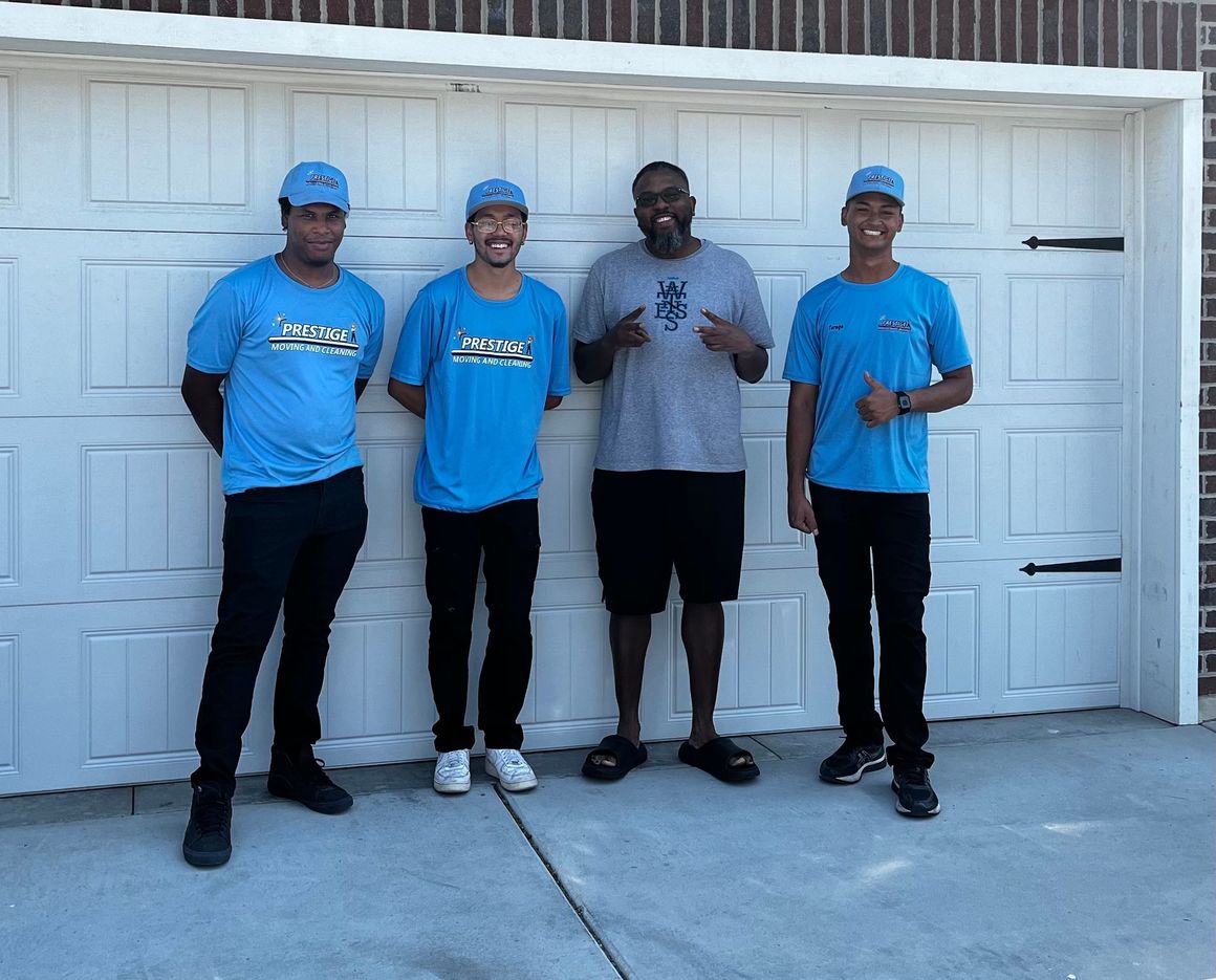 Four men in blue shirts are standing in front of a garage door