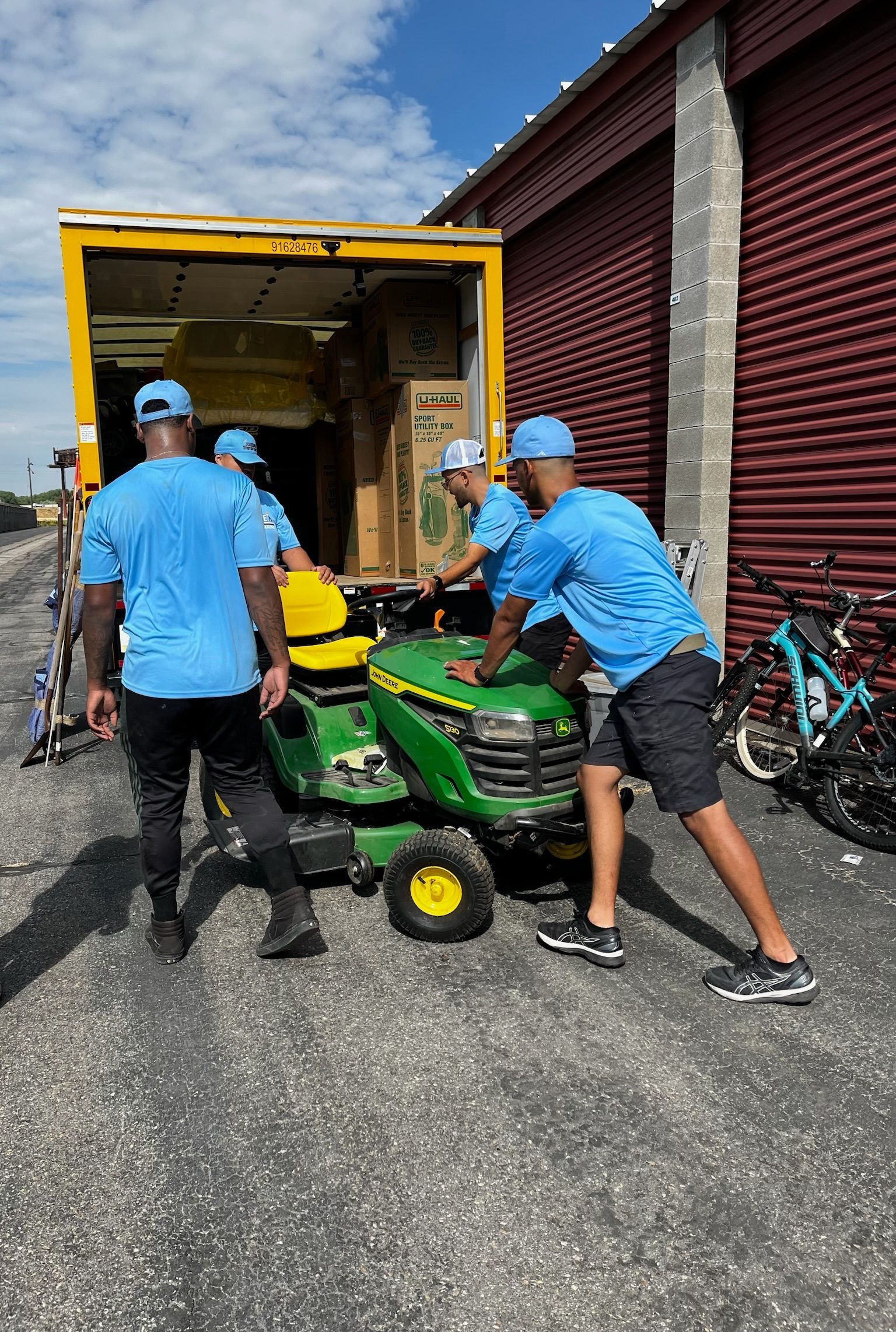 A group of men are pushing a lawn mower into a truck.