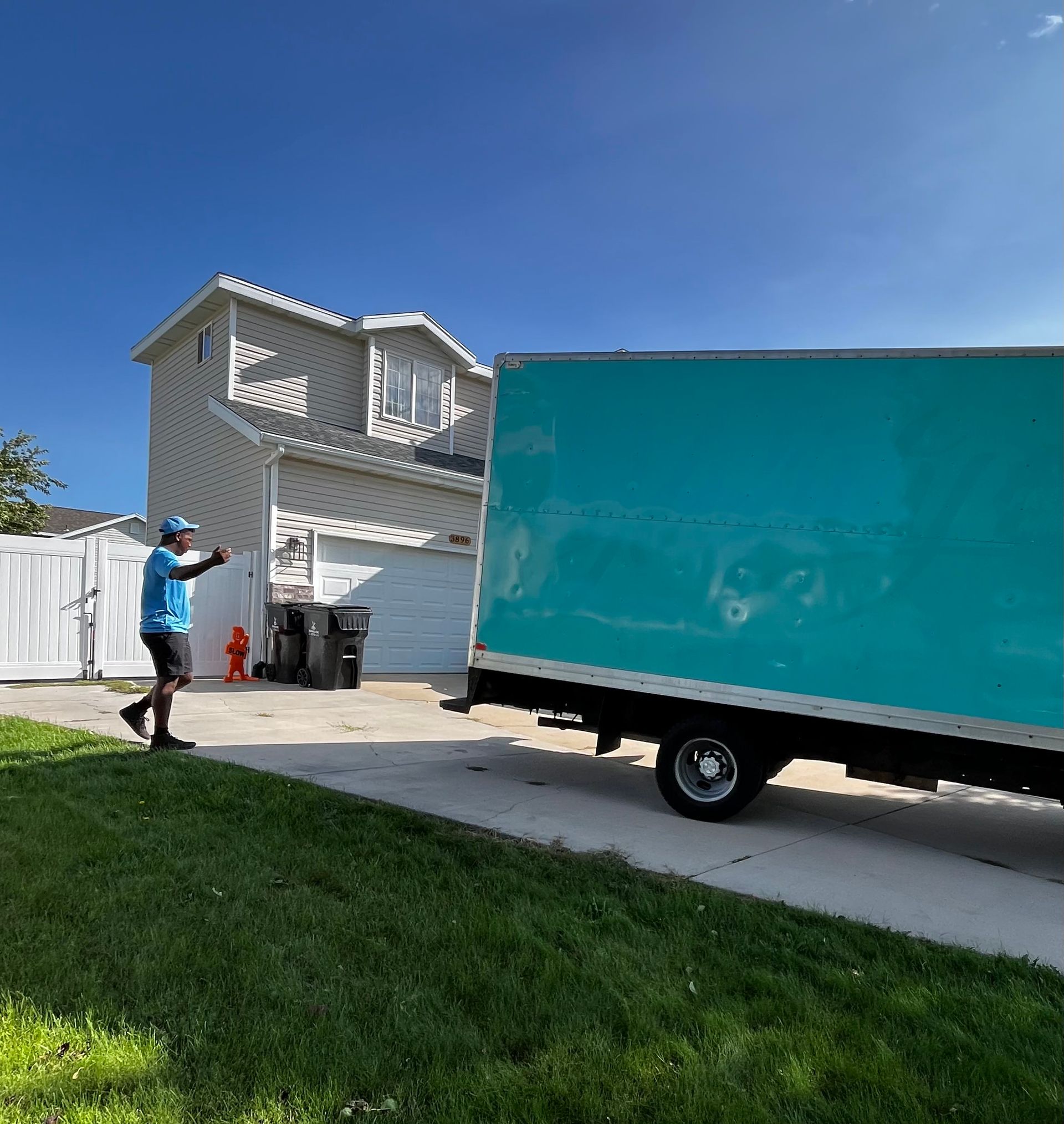 A man is walking towards a blue truck parked in front of a house.