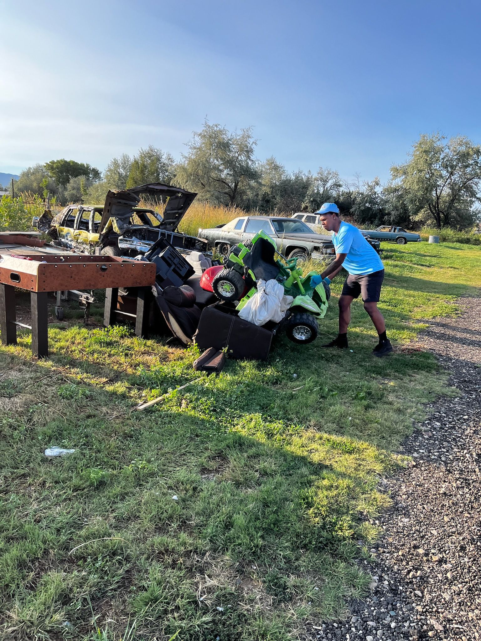 A man is standing in front of a pile of trash in a field.