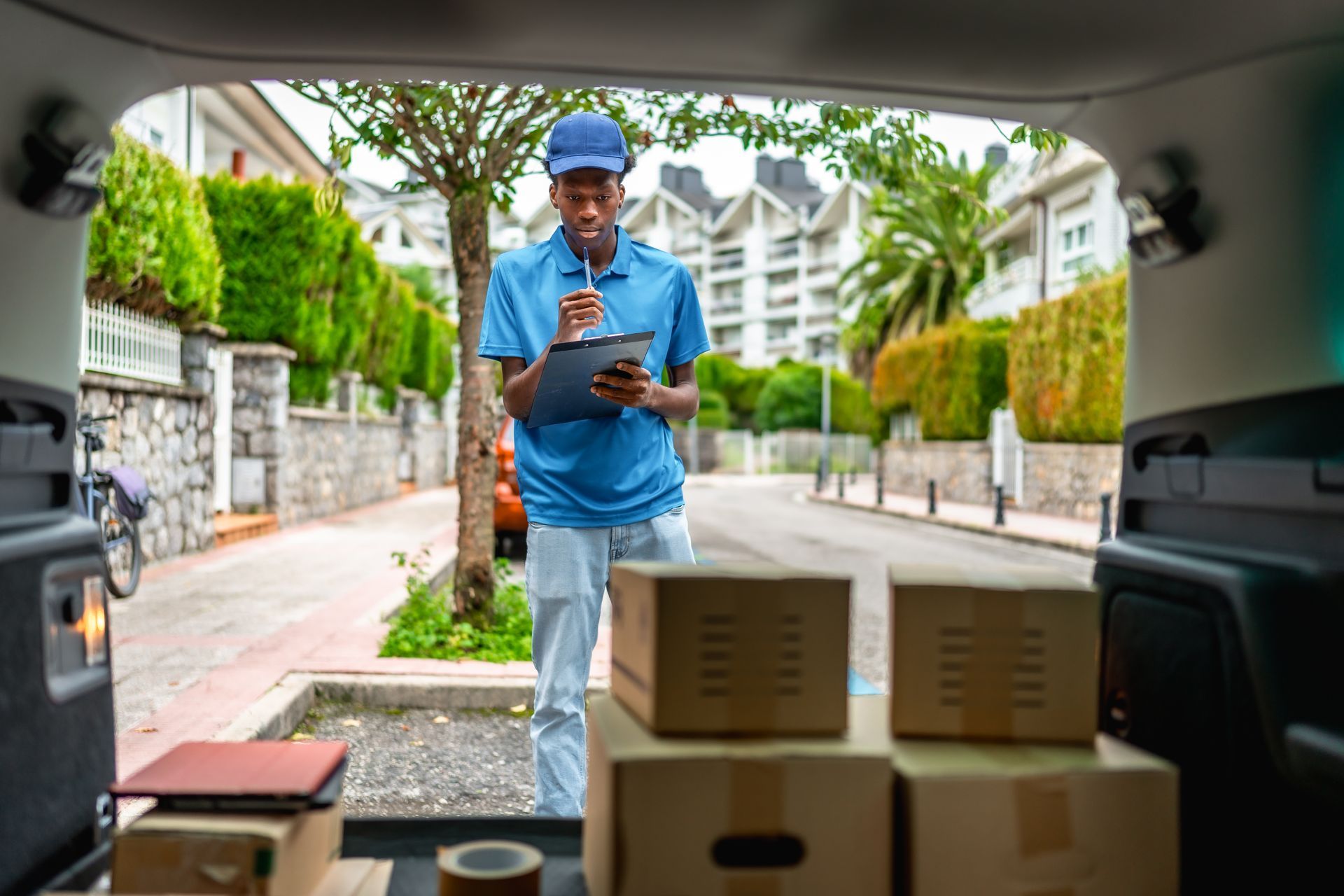 A delivery man is standing in the back of a car filled with boxes.
