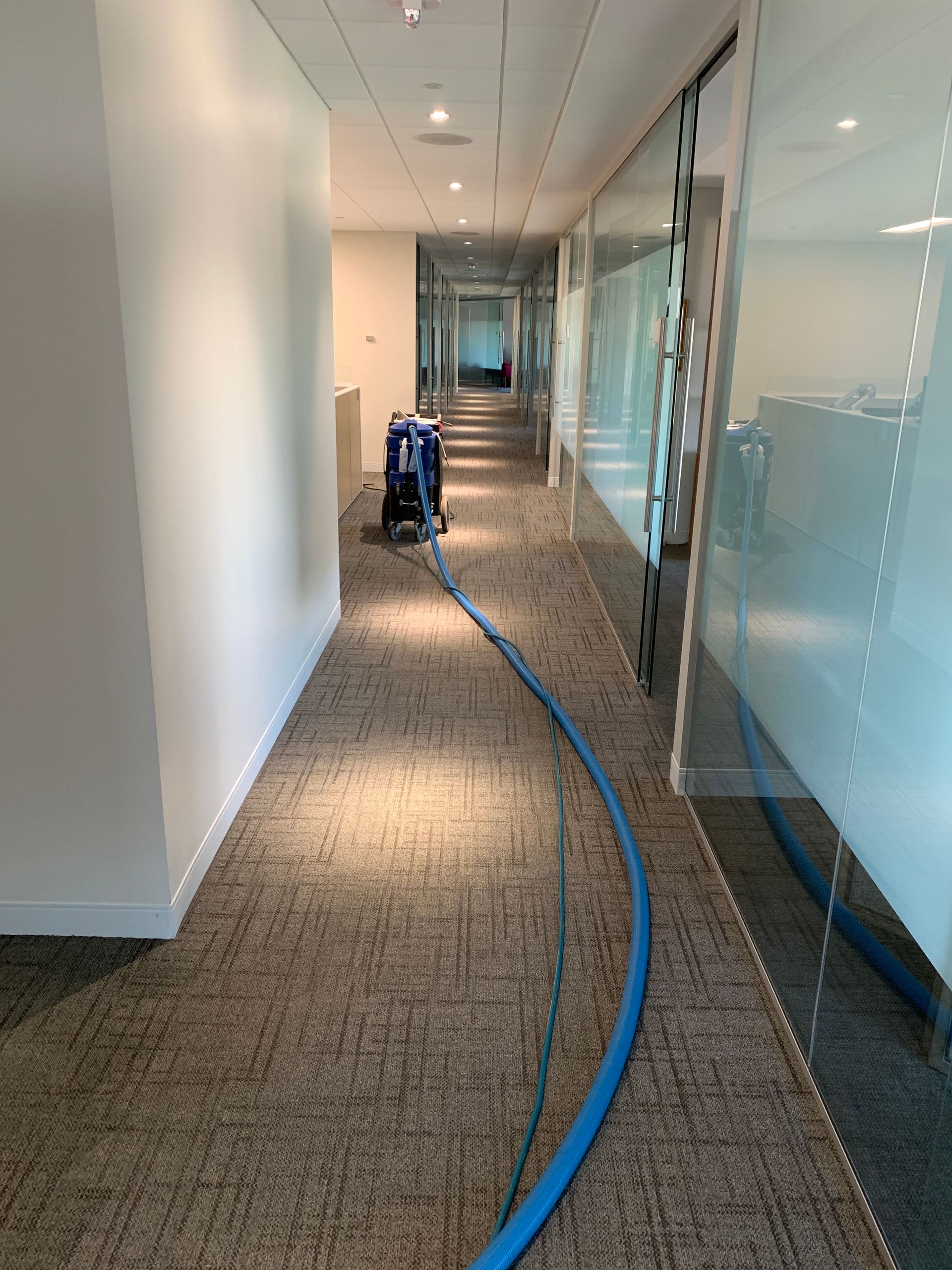 A long hallway with a vacuum cleaner in the middle of it.