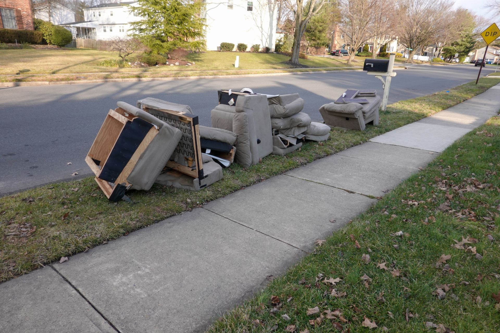A pile of furniture sits on the sidewalk next to a mailbox