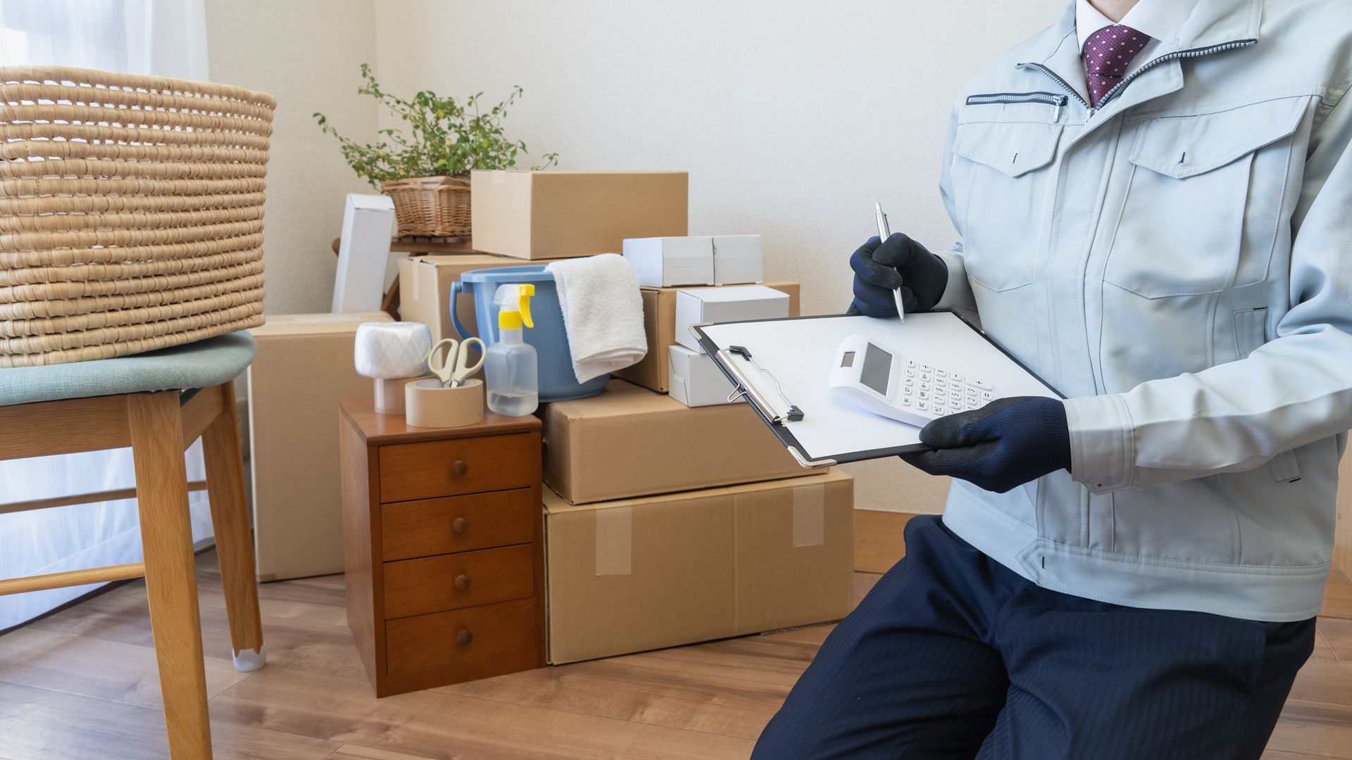 A man is holding a clipboard in front of a pile of cardboard boxes.