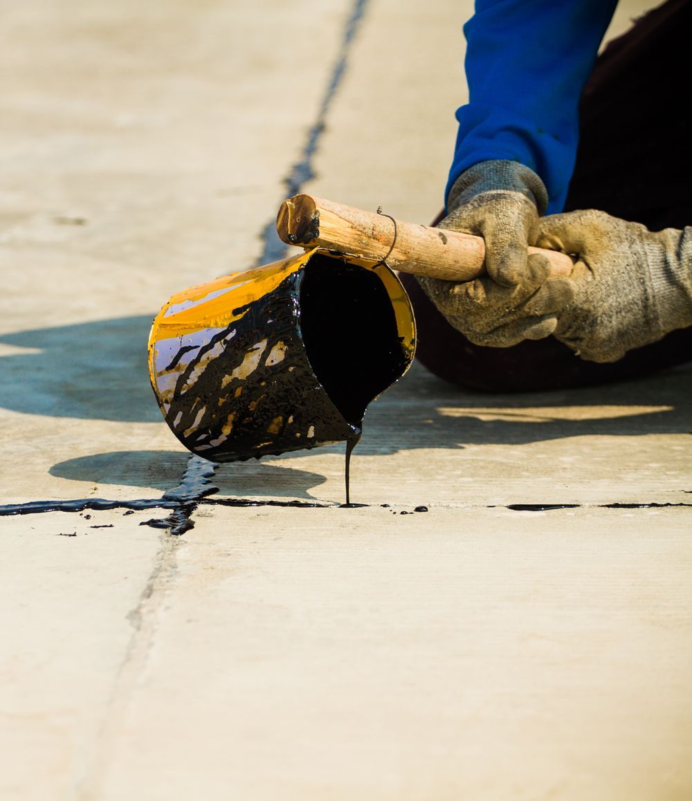 A person is pouring paint from a bucket onto a concrete surface A person is pouring paint from a bucket onto a concrete surface