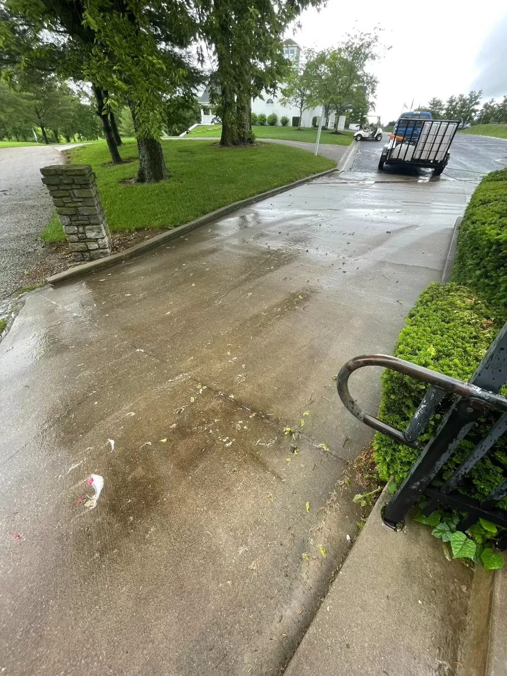 A car is driving down a wet sidewalk next to a park bench.