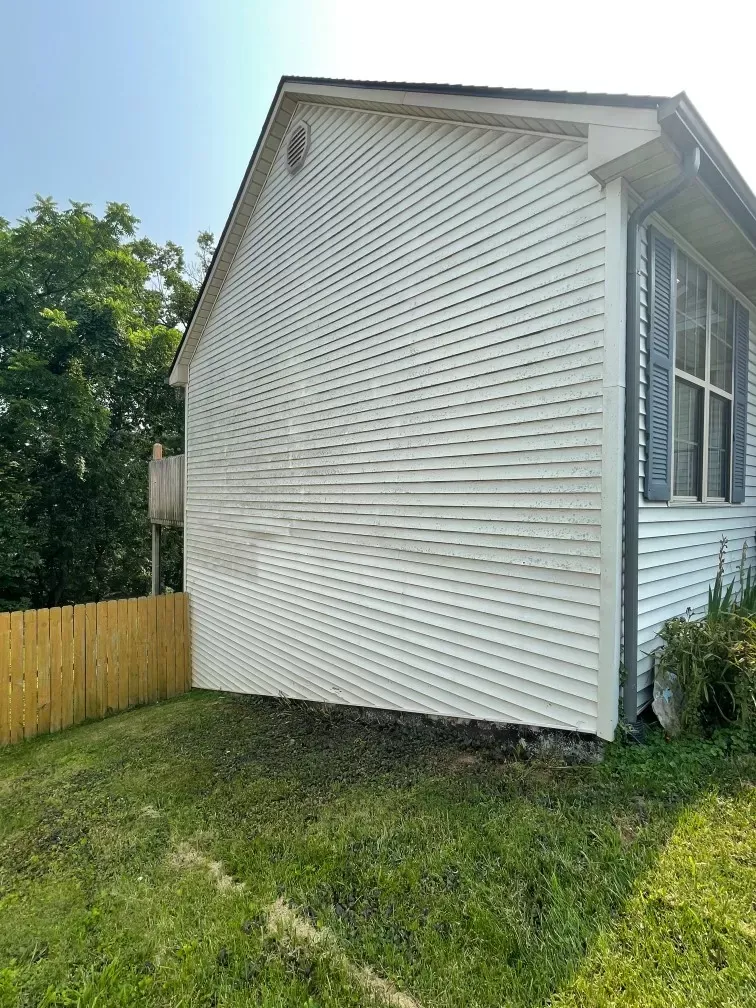 A white house with a wooden fence in the backyard.