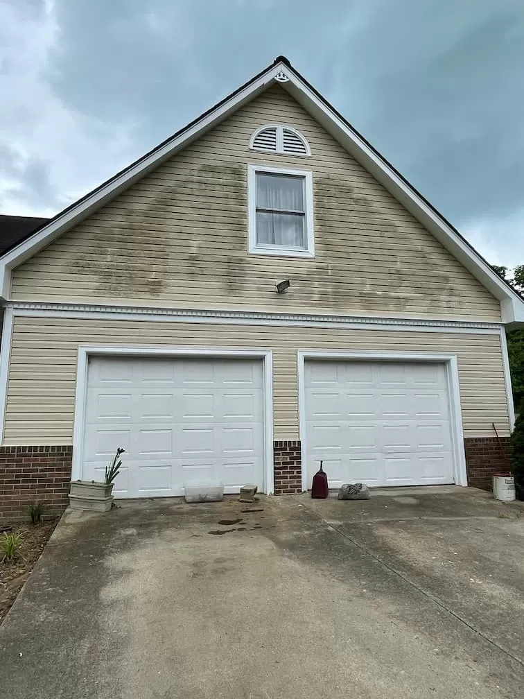 The front of a house with two garage doors and a window.
