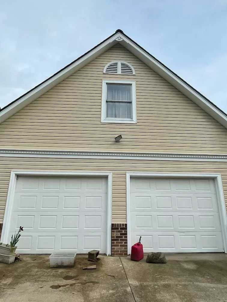 The front of a house with two garage doors and a window.