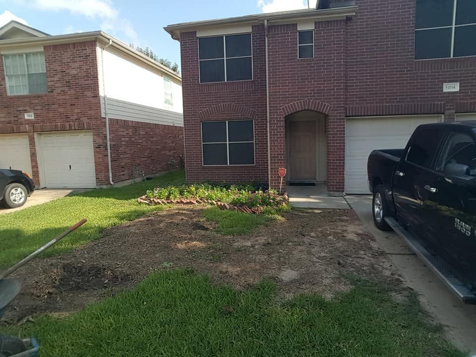 Front view of a brick townhouse with a garage, driveway, and small front yard landscaping.