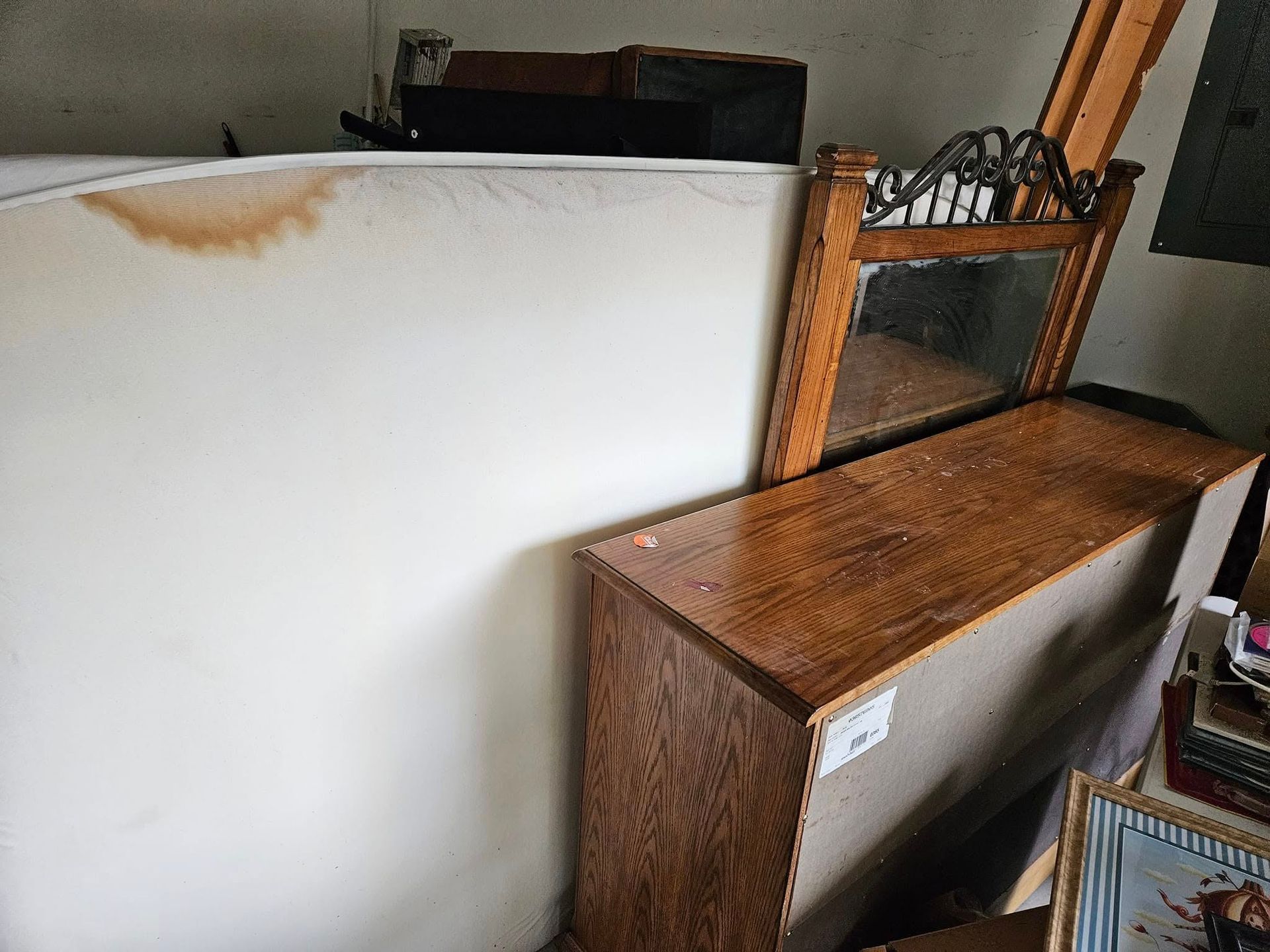 White panel leaning against a wooden desk and shelf in a cluttered indoor room.