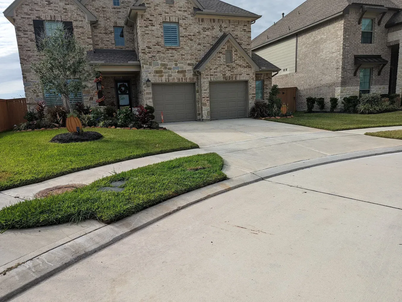 Suburban brick house with a two-car garage, driveway, and landscaped front lawn on a curved street