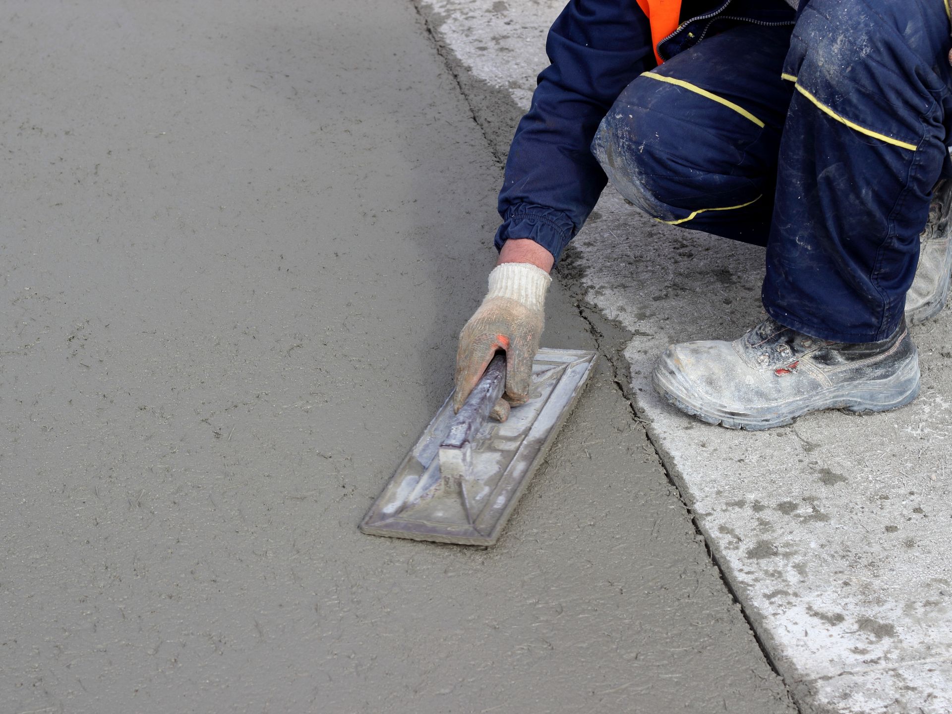 Worker trowel-finishing freshly poured concrete surface. Worker trowel-finishing freshly poured concrete surface.