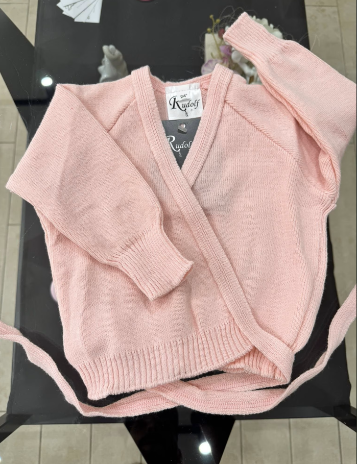 Maglione rosa avvolgente con maniche lunghe su un tavolo.