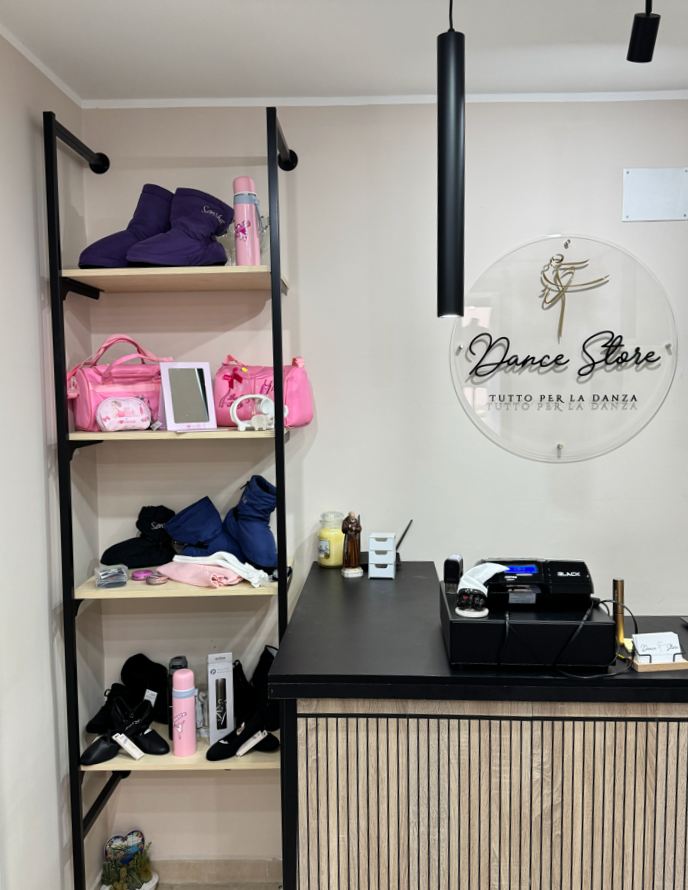 Interno di un negozio di danza con scaffali di abbigliamento da danza e un registratore di cassa.
