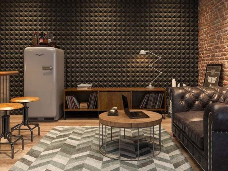 A living room with a couch , coffee table , stools and a refrigerator.