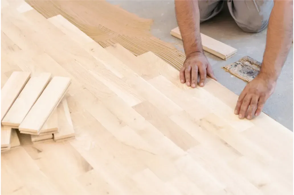 Ein Mann verlegt Holzdielen auf dem Boden.