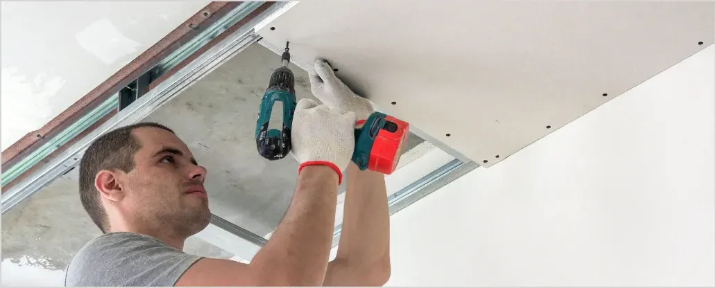 Ein Mann arbeitet mit einer Bohrmaschine an einer Decke.