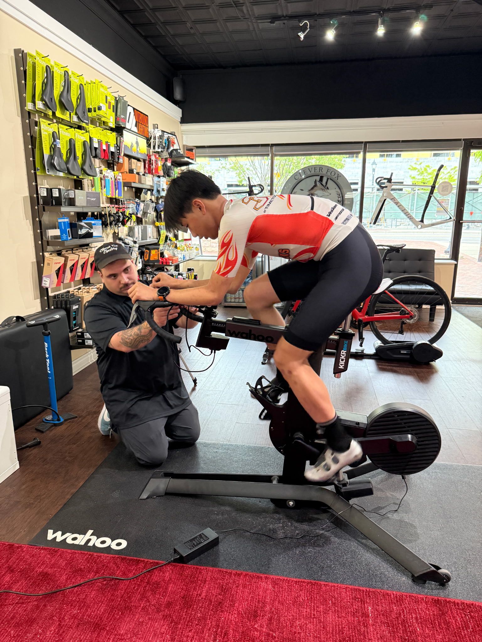 A bike fitter adjusts a rider on a stationary bike.