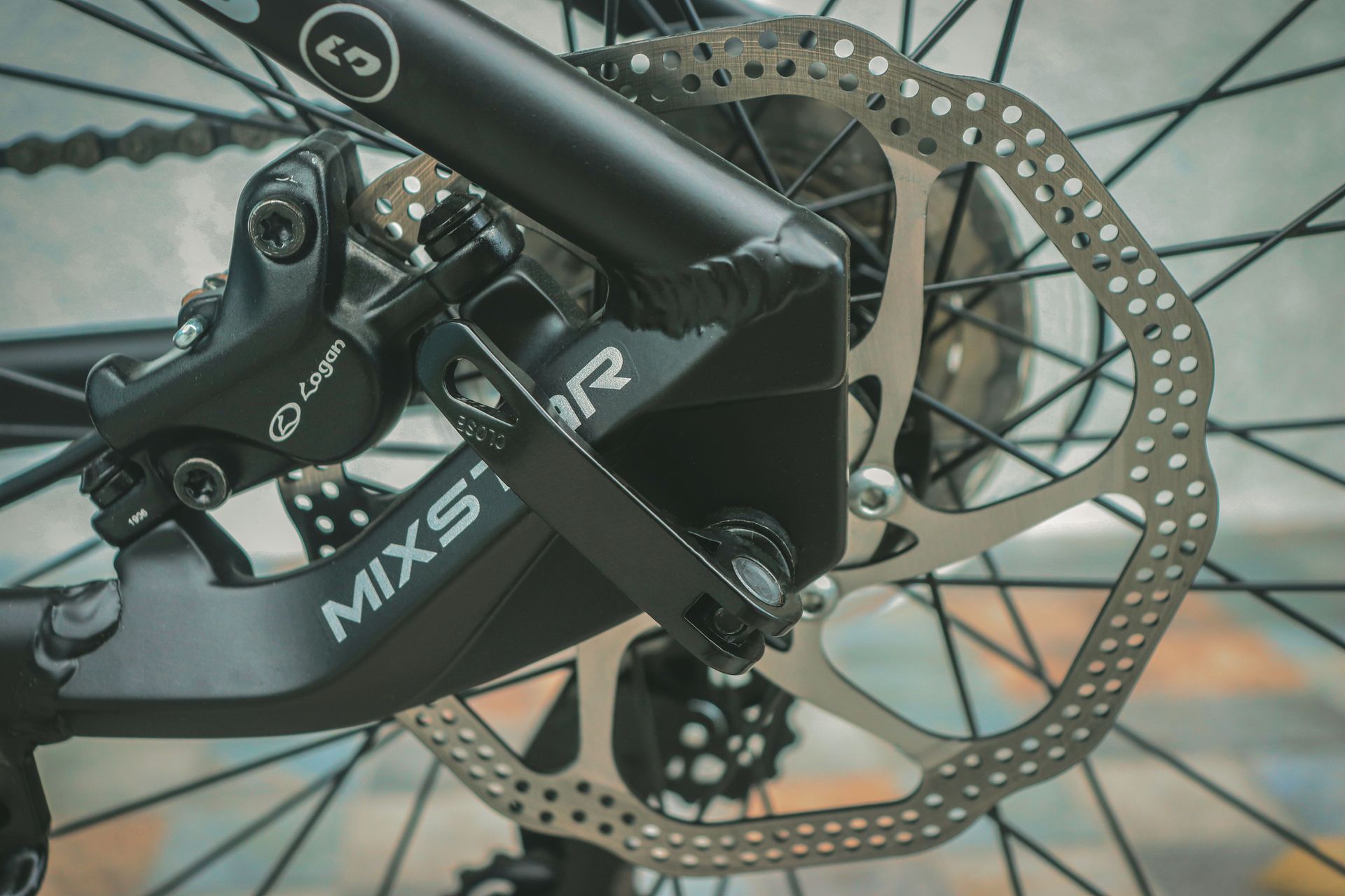 Close-up of a bike’s rear wheel, disc brake, and frame with a black bike bag attached