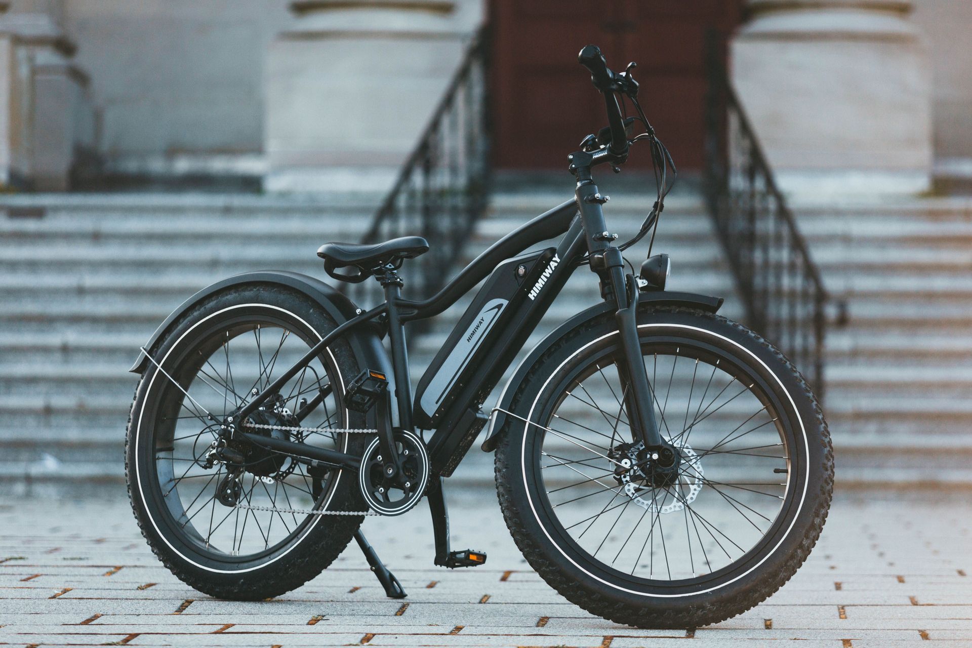 Black e bike parked on a city sidewalk in front of a stone building