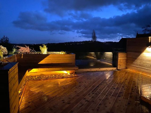 Roof top timber decking at dusk with built in deck lighting picking out the planters and steps