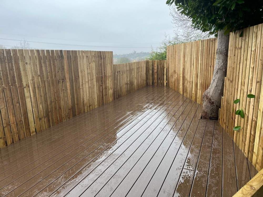 Closeboard fencing enclosing a brown composite deck cut around a mature tree on a sloping garden in Mosborough, Sheffield