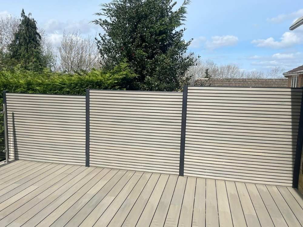 Cream slatted composite fence panels with anthracite aluminium posts fitted along the edge of a composite deck in Frecheville, Sheffield