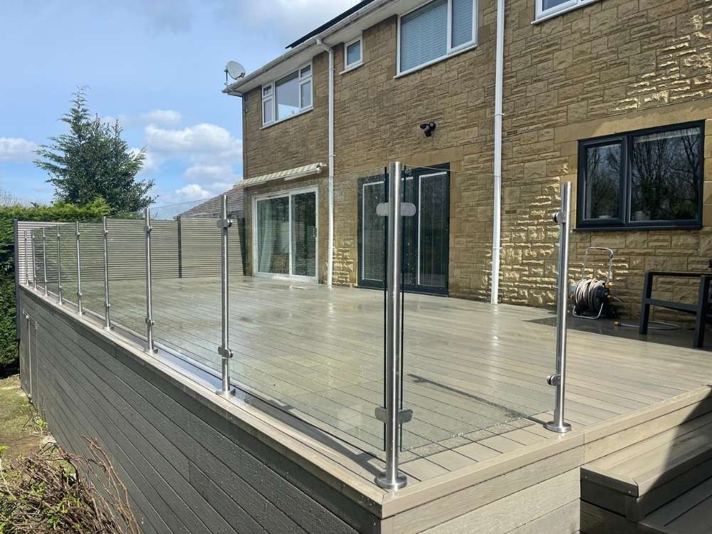 Frameless glass balustrade on stainless steel posts along the edge of a raised composite deck in Woodseats, Sheffield