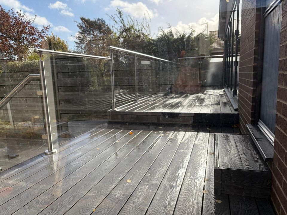 Two-level composite deck with a glass balustrade beside the house in Dore, Sheffield