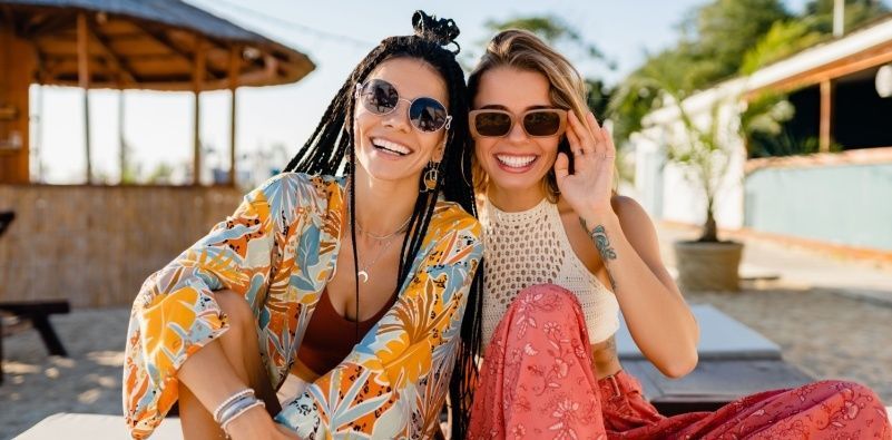 Two women sat in the sunshine wearing fashionable sunglasses